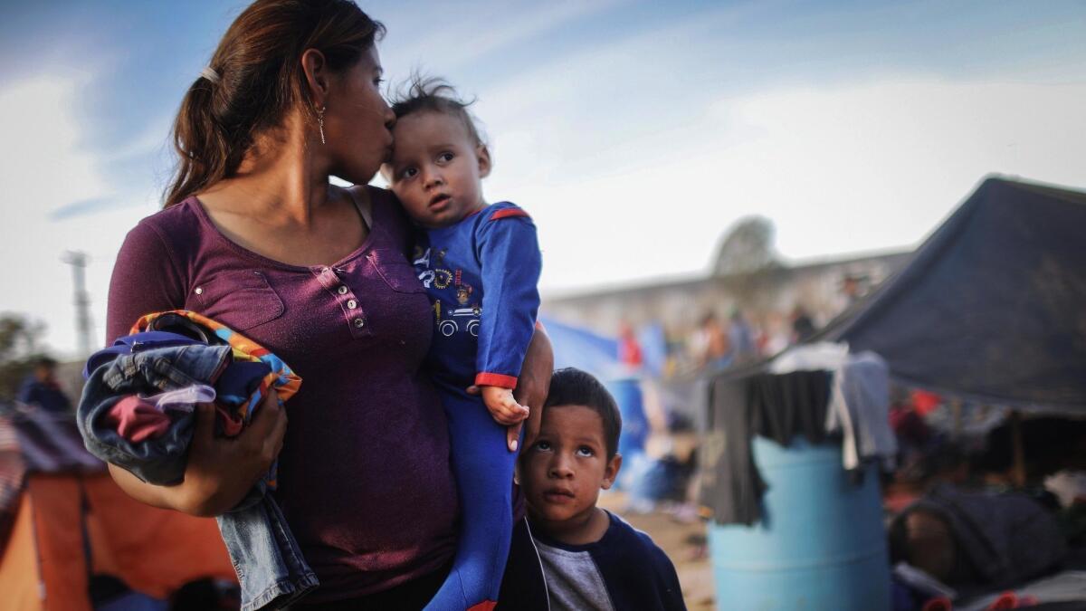 TIJUANA, MEXICO - NOVEMBER 21: A Honduran mother stands with her sons at a temporary shelter for members of the 'migrant caravan', located within sight of the U.S.-Mexico border barrier, on November 21, 2018 in Tijuana, Mexico. Parts of the migrant caravan have been arriving to Tijuana from Mexicali after traveling for more than a month through Central America and Mexico to reach the U.S. border. A US federal judge has temporarily blocked President Trump's order which attempted to deny migrants the possibility of asylum if they cross the border illegally. (Photo by Mario Tama/Getty Images) ** OUTS - ELSENT, FPG, CM - OUTS * NM, PH, VA if sourced by CT, LA or MoD **