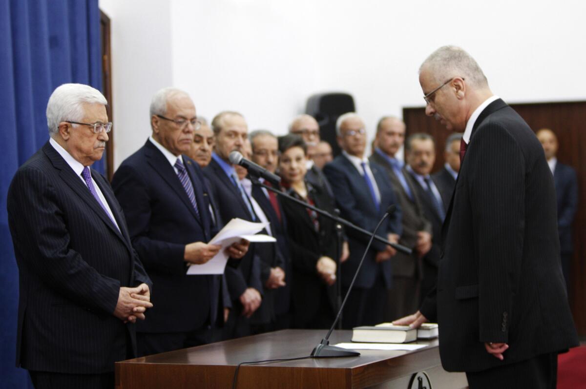 Palestinian Prime Minister Rami Hamdallah, right, takes the oath of office in front of President Mahmoud Abbas, left, and other officials in the West Bank city of Ramallah.