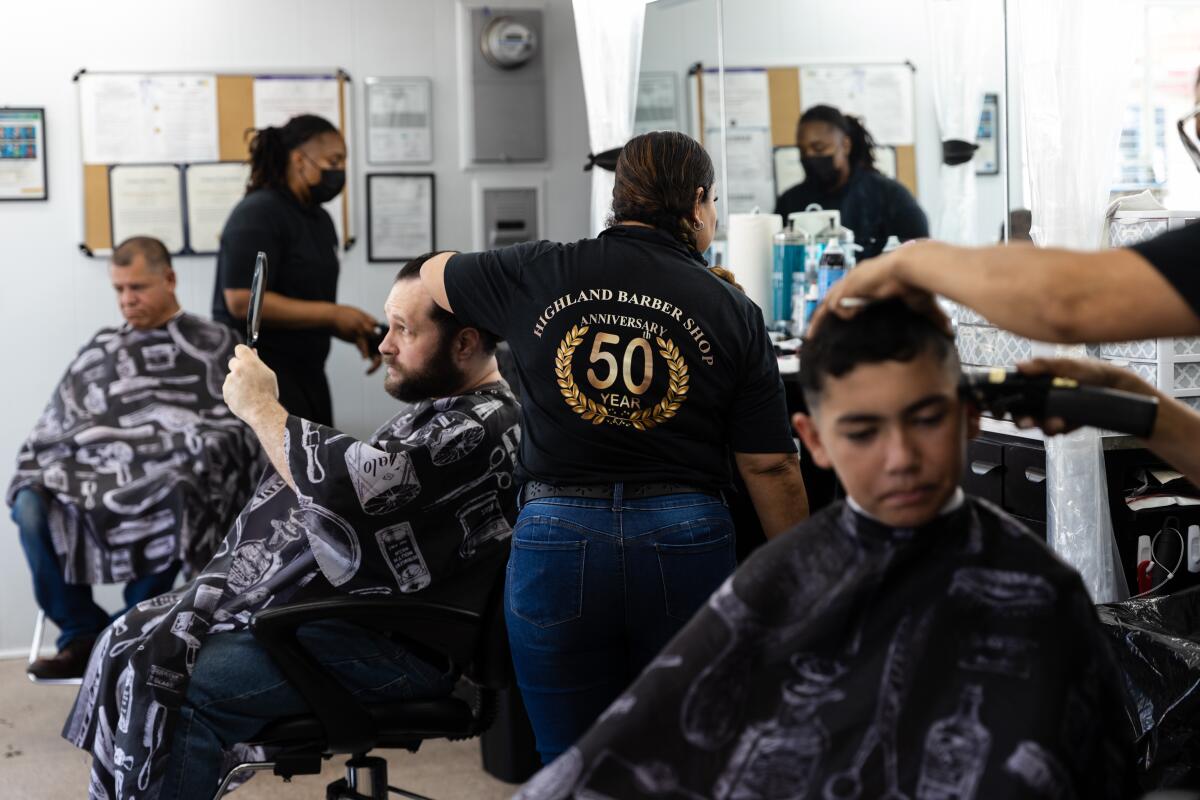 Ryan Marsh holds up a mirror to check out his new haircut at the Highland Barber Shop in National City on July 16.