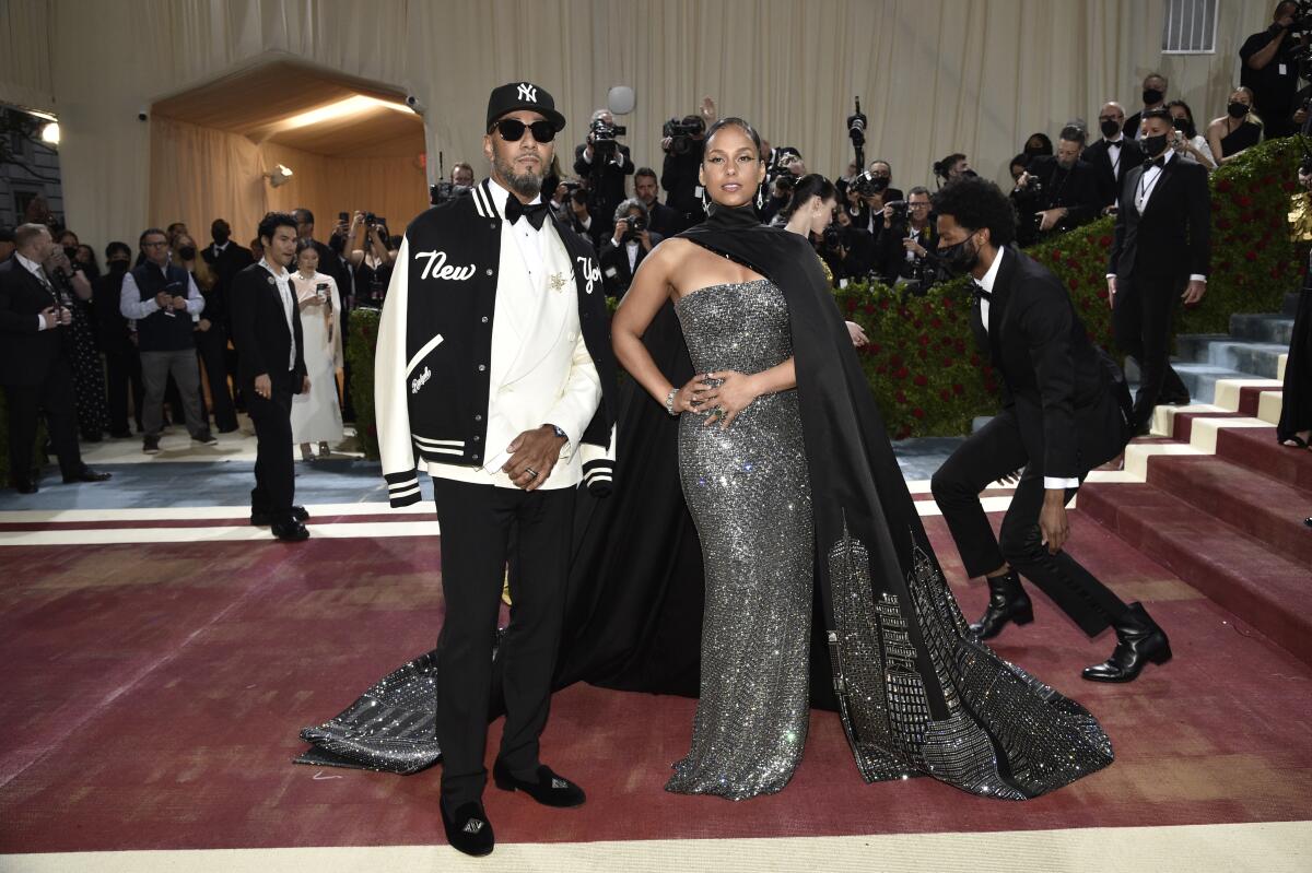 Swizz Beat poses in a varsity jacket over a white-jacket tux next to Alicia Keys in a sparkly gown and a black bedazzled cape