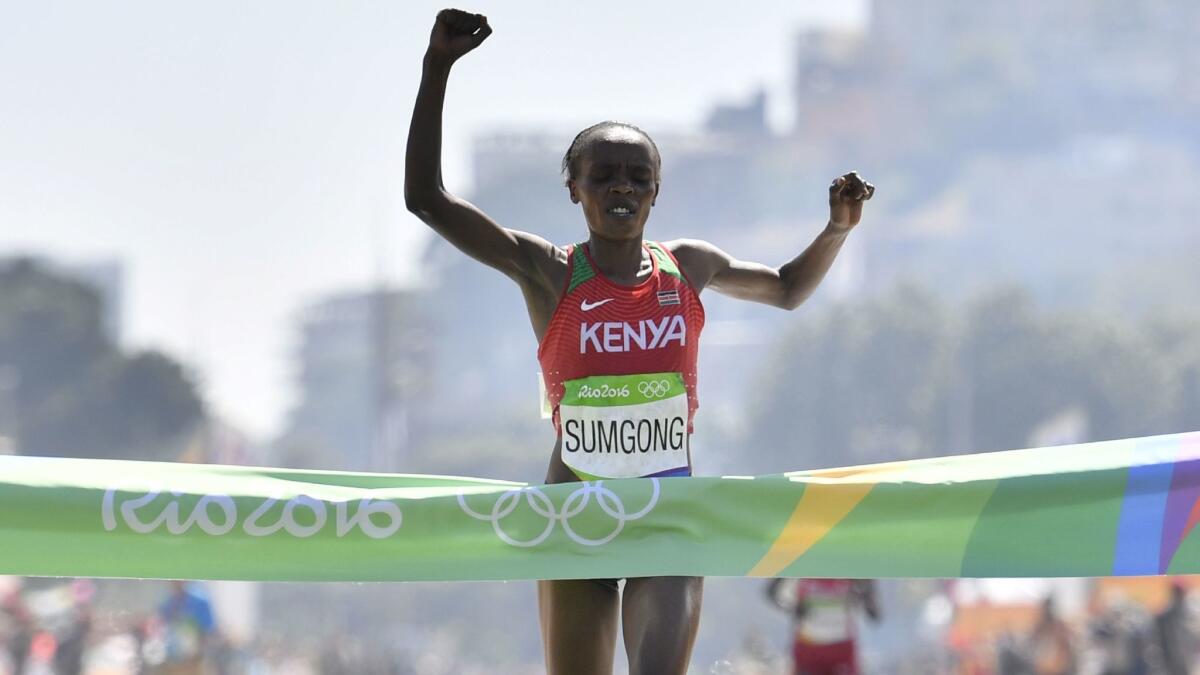 Kenya's Jemima Sumgong raises her arms in victory as she crosses the finish line of the women's marathon at the 2016 Summer Olympics in Rio de Janeiro.