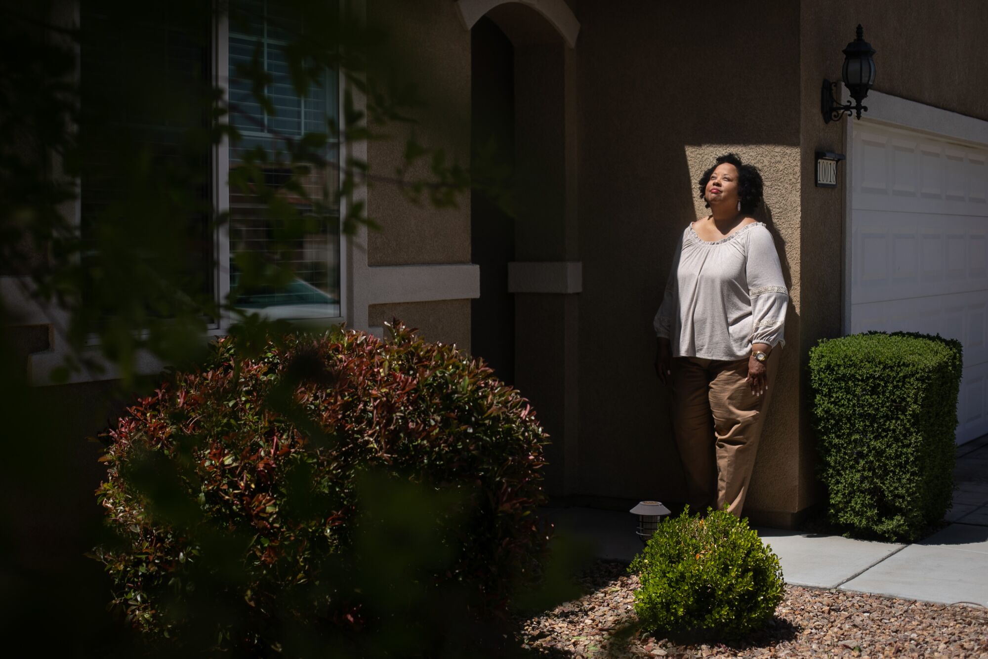 A woman stands outside her house in Apple Valley, Calif.