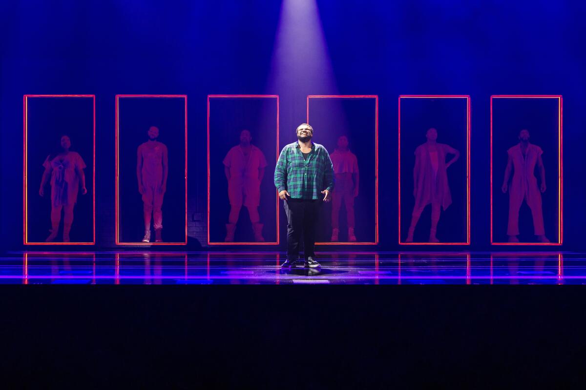 Jaquel Spivey is shown standing on a stage before a series of red neon rectangles