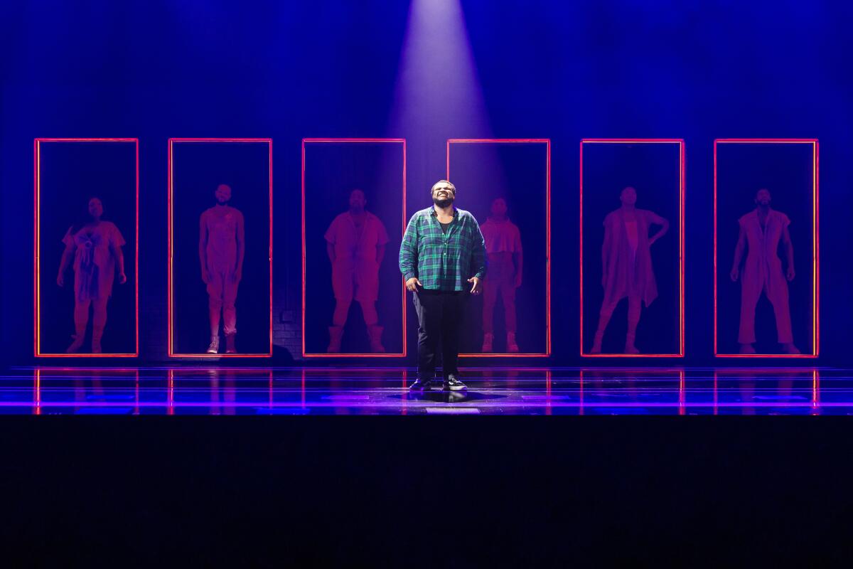 Jaquel Spivey is shown standing on a stage before a series of red neon rectangles