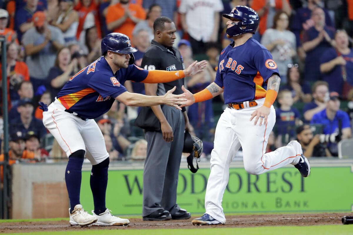 Houston Astros' Chas McCormick, left, and Christian Vazquez, right, celebrate as they both scored on an RBI-double by Jose Altuve during the second inning of a baseball game against the Oakland Athletics, Sunday, Aug. 14, 2022, in Houston. (AP Photo/Michael Wyke)