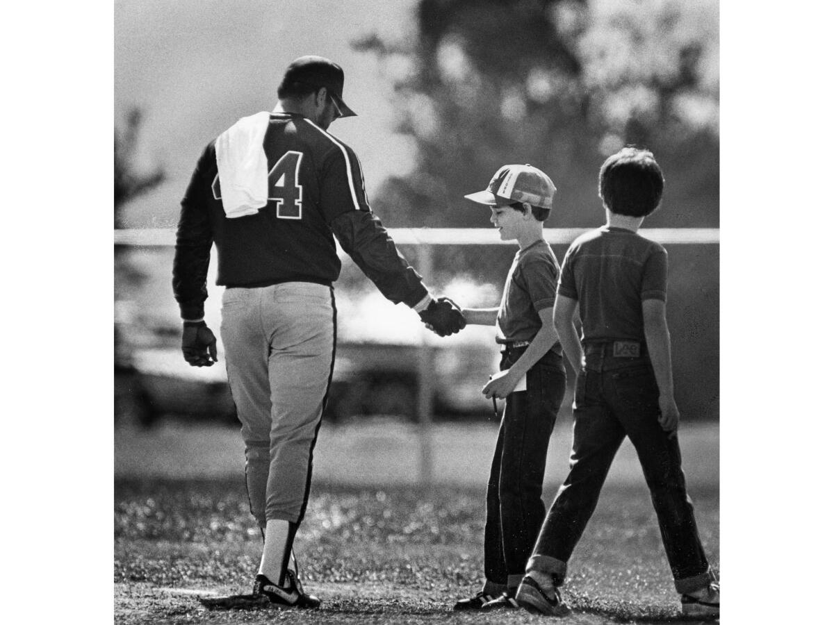 March 1983: Angels slugger Reggie Jackson shakes hands with a young admirer before leaving the practice field.