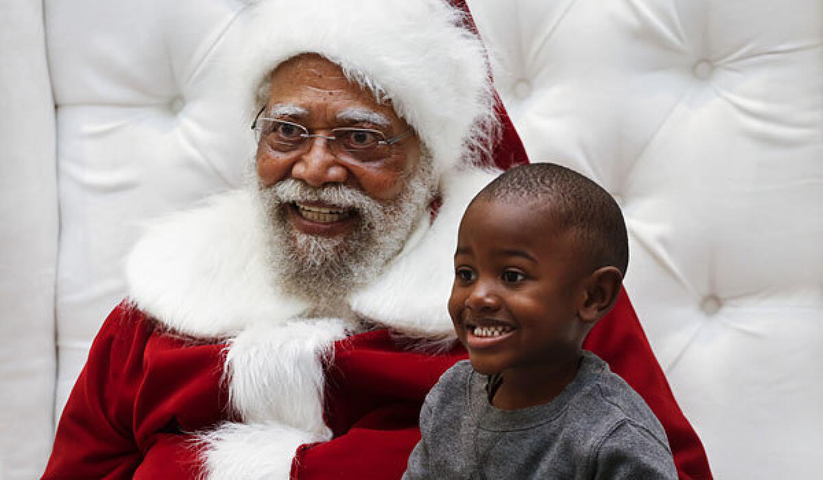 Jahleel Logan, 3, poses with Santa, a.k.a. Langston Patterson, 78, of Rudolph Holiday Photo, at the Baldwin Hills Crenshaw Plaza.