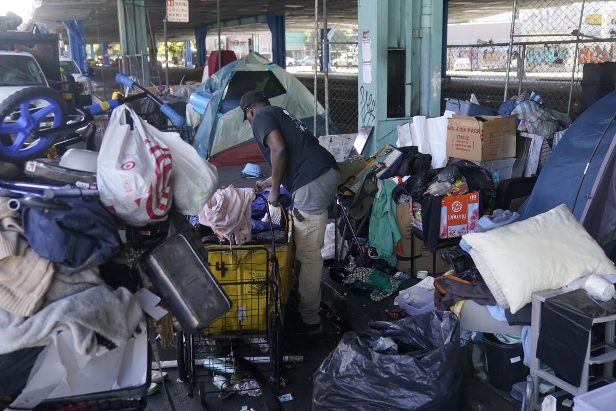 A homeless man gathers his possessions from a large pile. 