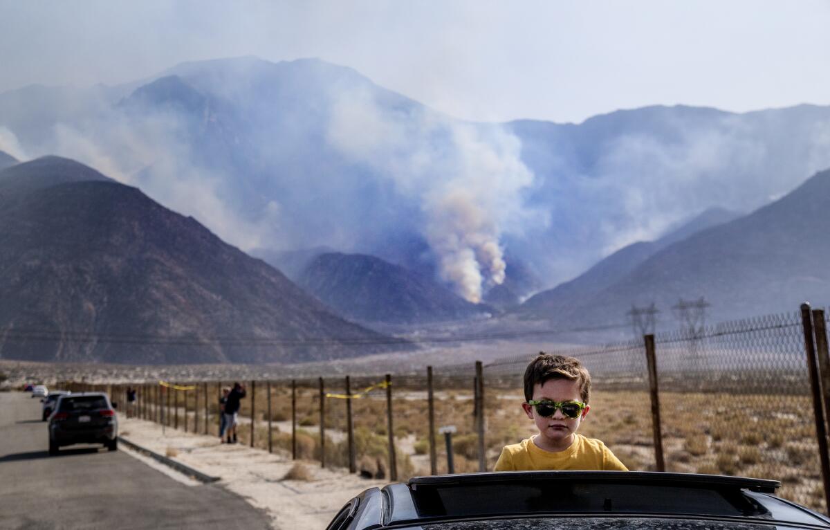 Elias Lomeli of Desert Hot Springs watches firefighting helicopters refill with water from his car's sunroof.