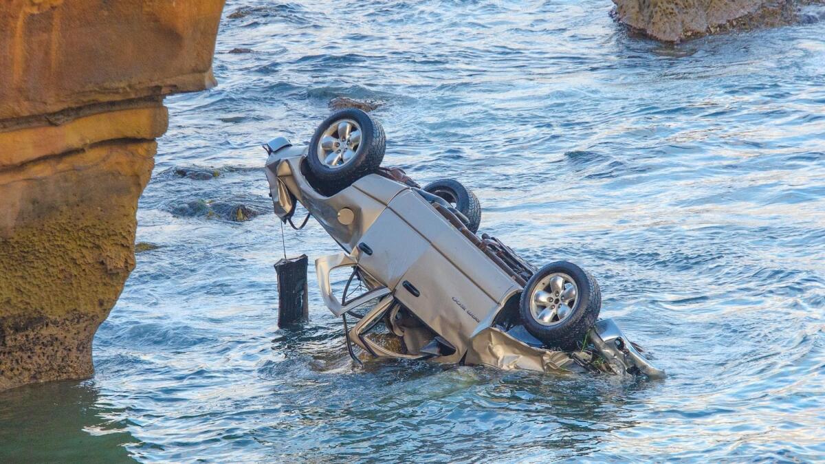 The wreckage of a pickup is upside down in the water after going over the edge at Sunset Cliffs on June 13.