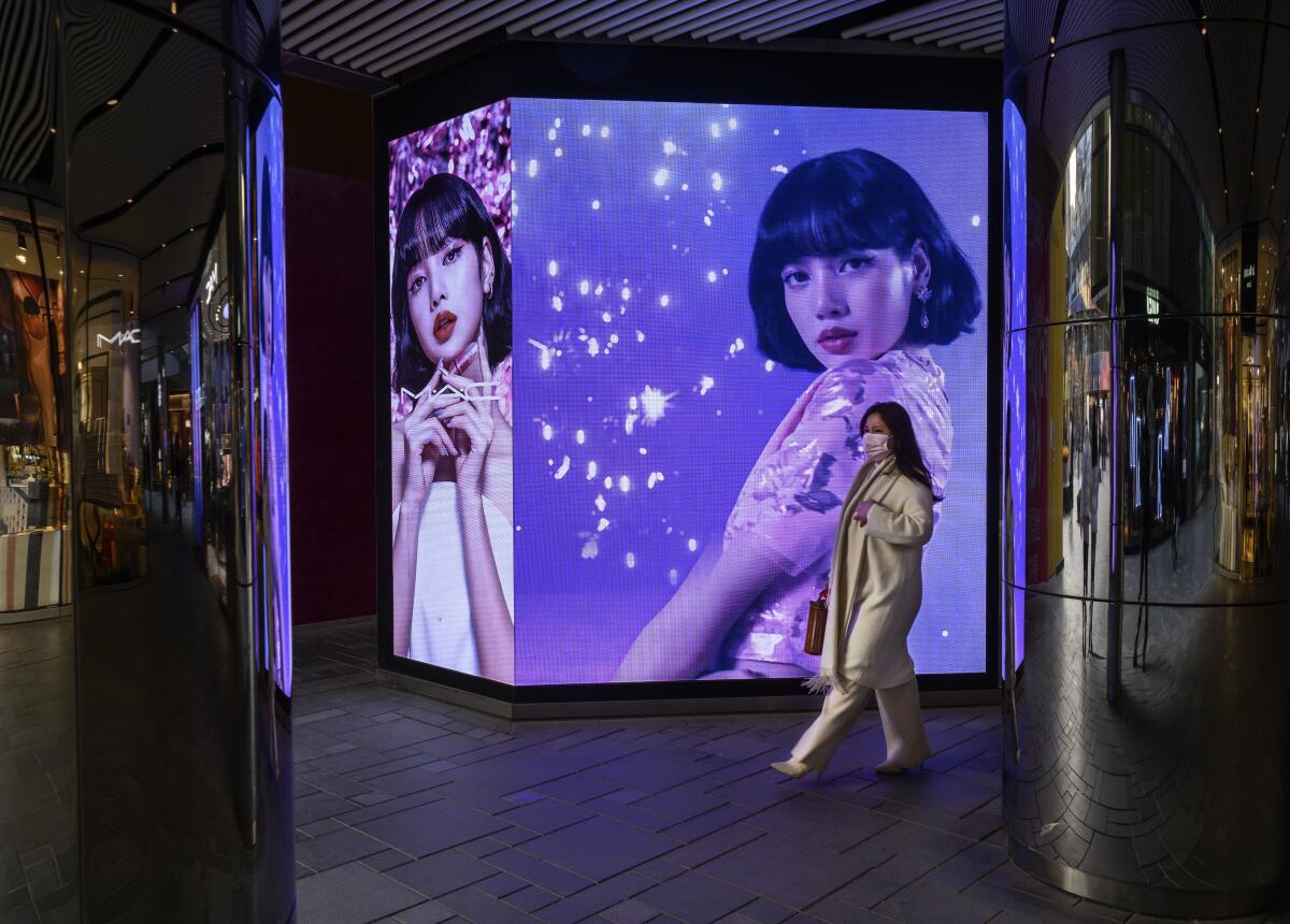 A woman walks by an ad at a shopping mall.