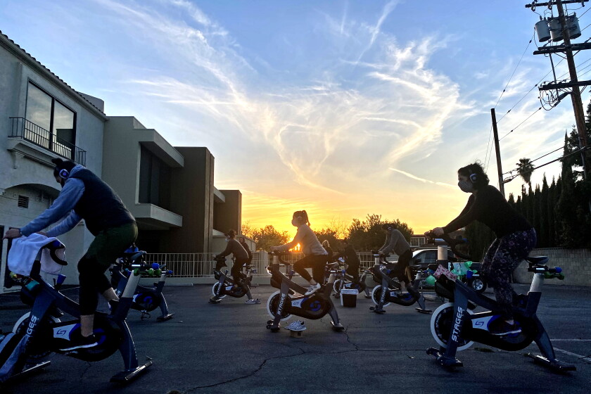 As L.A. eyes orange coronavirus tier, is another wave of
reopenings around the corner? 2 Cyclists do a socially distanced workout outside in a parking lot near Rev Cycle's San Marino studio.