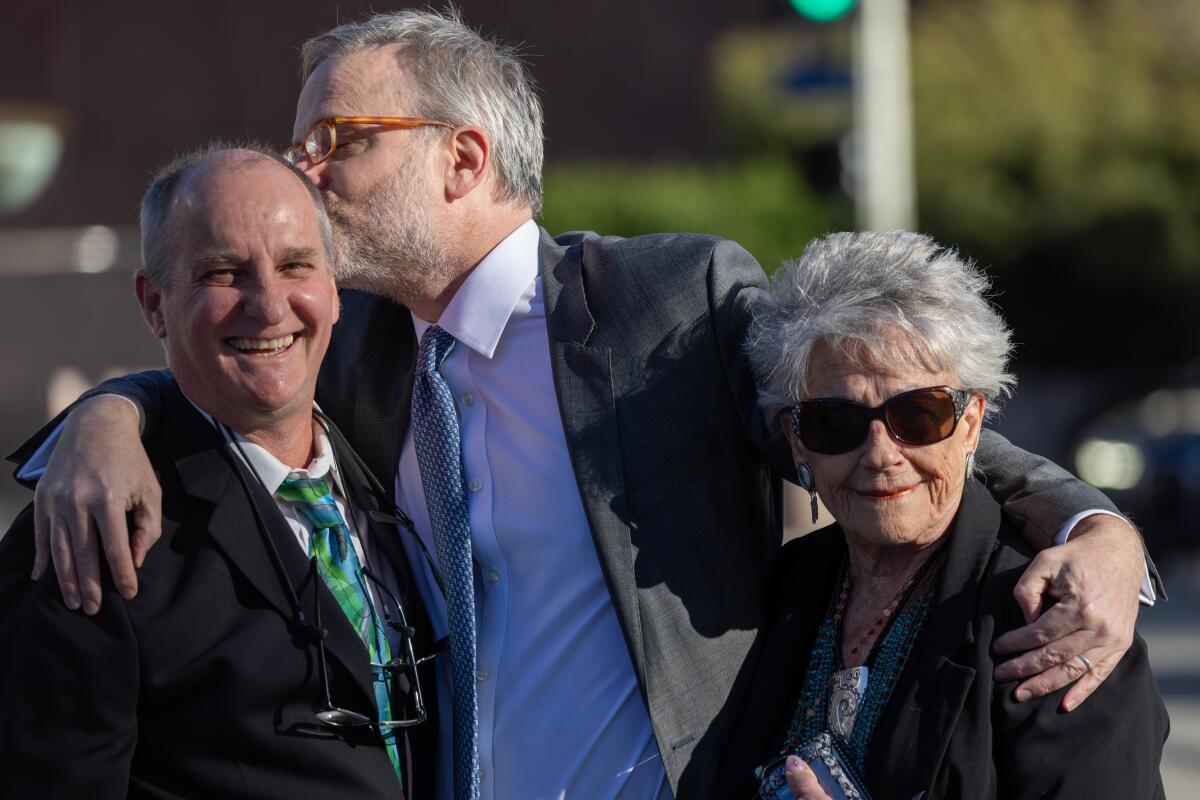 Two men and a woman celebrate outside a federal courthouse