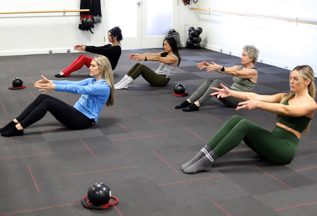 Monica Grubin, left, stretches with fellow instructors and members of Pure Barre Huntington Beach on Tuesday.