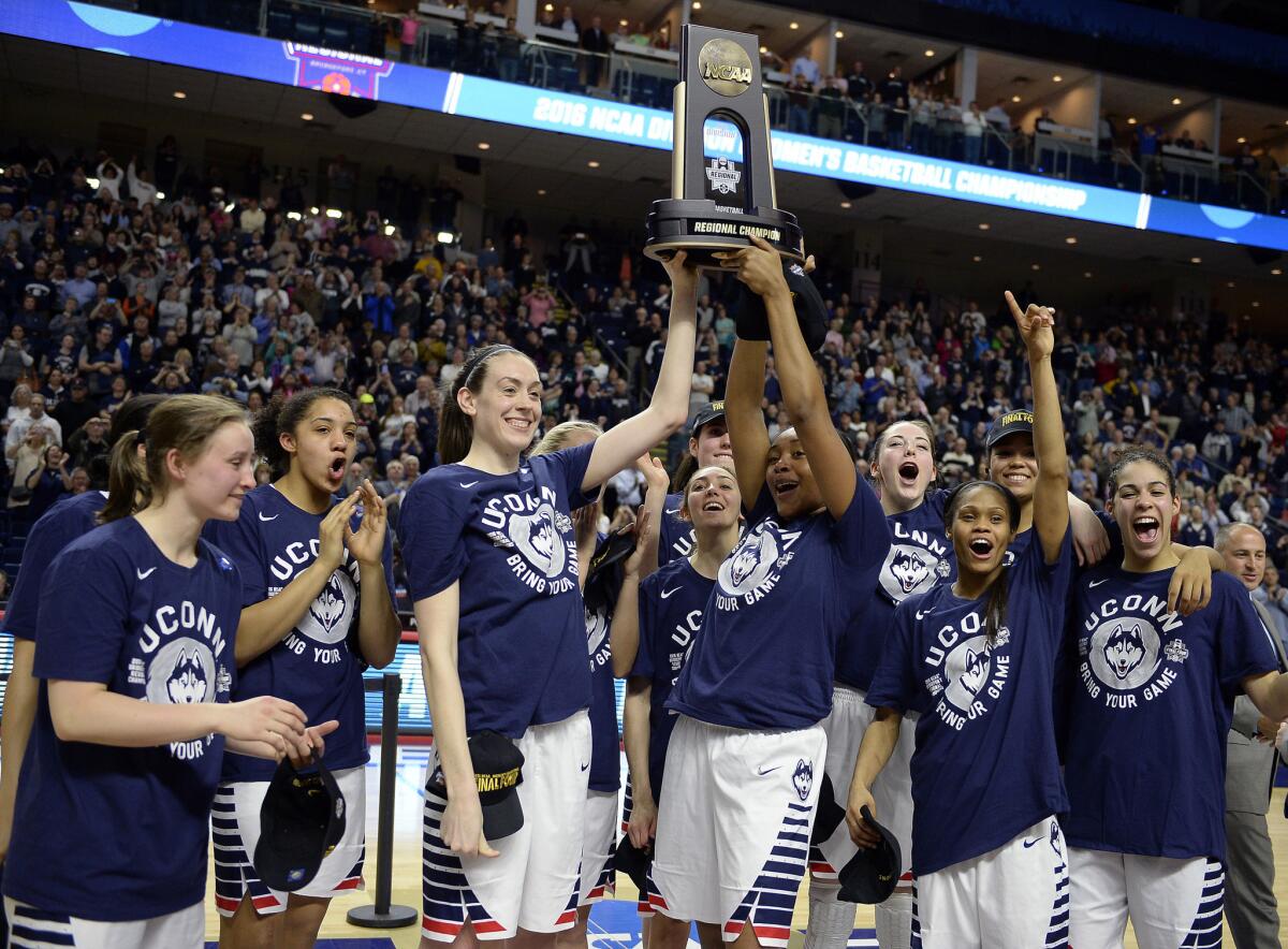 Connecticut's Breanna Stewart, left, and Morgan Tuck hoist the trophy and celebrate with their teammates after defeating Texas, 86-65, in the East Regional final.
