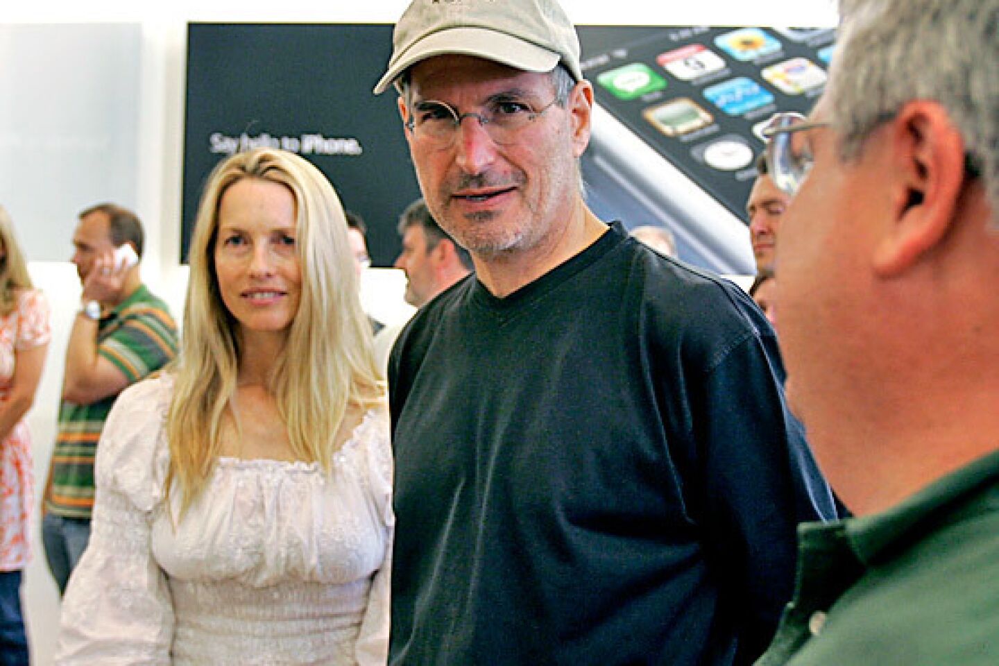 Jobs and his wife, Laurene Powell, meet with customers after the launch of the iPhone.