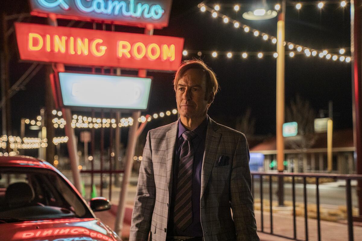 Bob Odenkirk as Jimmy McGill walks among neon signs at night in "Better Call Saul."