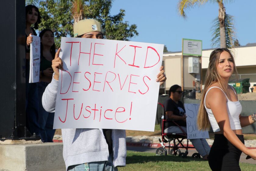 Vista, CA - September 14: Protesters hold signs along Bobier Drive in front of Vista High School in support of a Latino student that was allegedly assaulted by football players. (Charlie Neuman / For The San Diego Union-Tribune)
