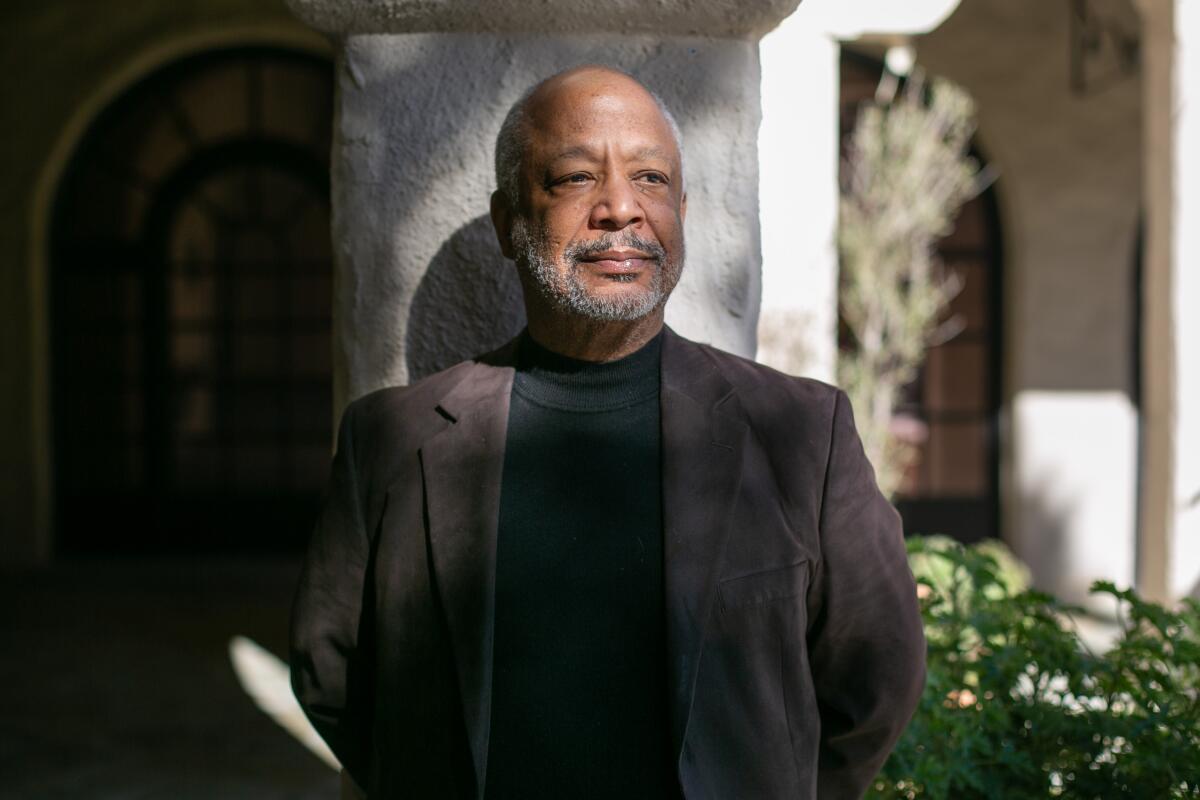 man in a turtleneck and jacket stands outside 