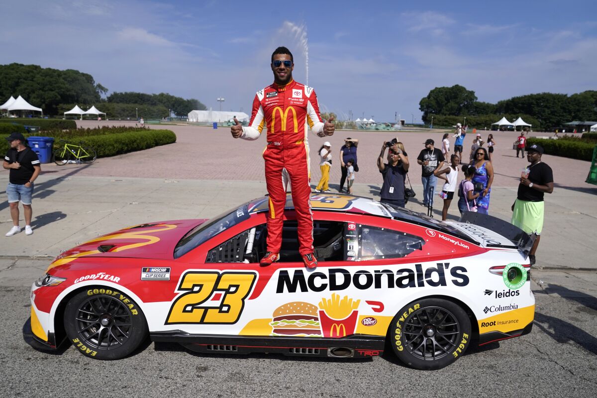 NASCAR driver Bubba Wallace poses for photographers near Buckingham Fountain on Tuesday, July 19, 2022, in Chicago during a promotional visit to announce a NASCAR Cup Series street race in the city, to be held July 2, 2023. (AP Photo/Charles Rex Arbogast)