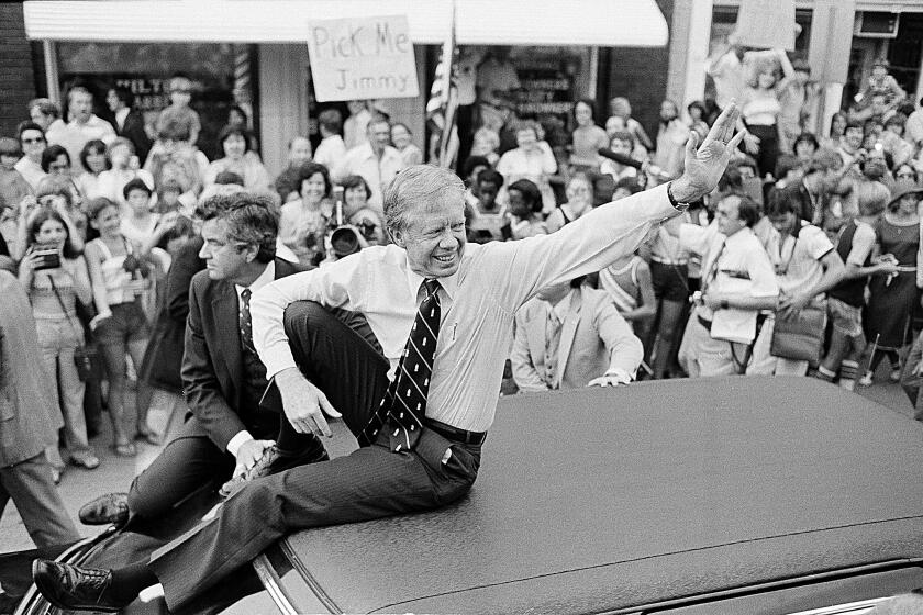 FILE - In this July 31, 1979, file photo, President Jimmy Carter waves from the roof of his car along the parade route through Bardstown, Ky. Carter is sometimes called a better former president than he was president. The backhanded compliment has always rankled Carter allies and, they say, the former president himself. Yet now, 40 years removed from the White House, the most famous resident of Plains, Georgia, is riding a new wave of attention as biographers, filmmakers, climate activists and Carter’s fellow Democrats push for a recasting of his presidential legacy. (AP Photo/Bob Daugherty, FIle)