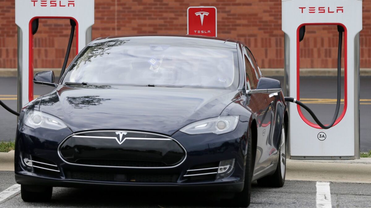 Tesla said it's locating the new stations near grocery stores and shopping areas so owners can run errands while they charge their vehicles. Above, a Tesla vehicle recharges at a station in Charlotte, N.C.