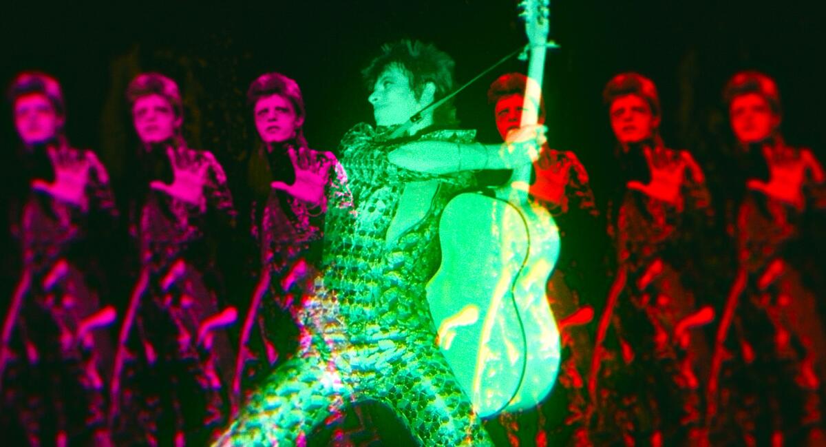 A man dressed and lit in green holds a guitar, with a line of six similar figures in red behind him.
