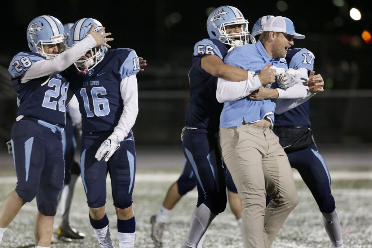 Corona del Mar offensive coordinator Kevin Hettig celebrates with Cole Rener (56) and Blake Byers (17) after beating Grace Brethren 56-28 to win the CIF Southern Section Division 3 crown on Friday at Newport Harbor High.