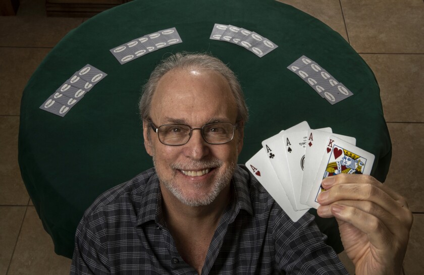 Steve Forte today holds four aces and a king and smiles into the camera, with a card table in the background.