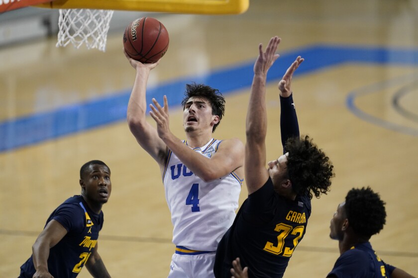 UCLA guard Jaime Jaquez Jr. (4) shoots next to Marquette forward Dawson Garcia (33) during the second half of an NCAA college basketball game Friday, Dec. 11, 2020, in Los Angeles. (AP Photo/Ashley Landis)