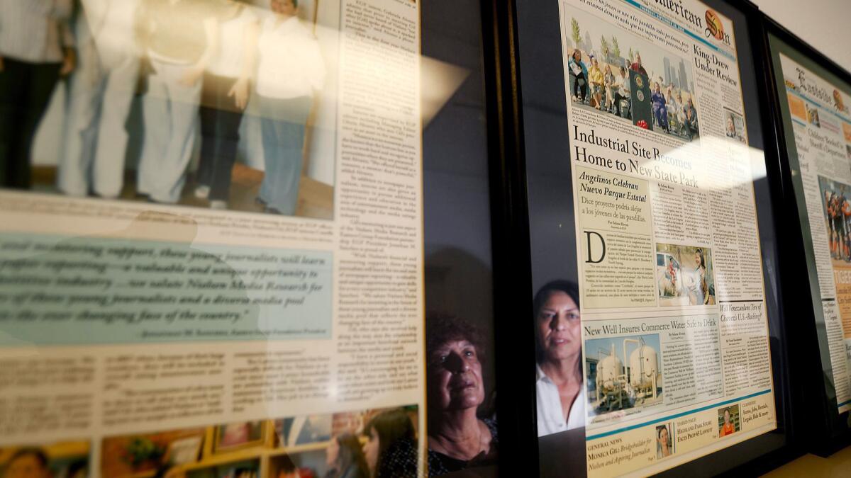 Dolores Sanchez and Gloria Alvarez are reflected in the glass of framed newspaper pages.