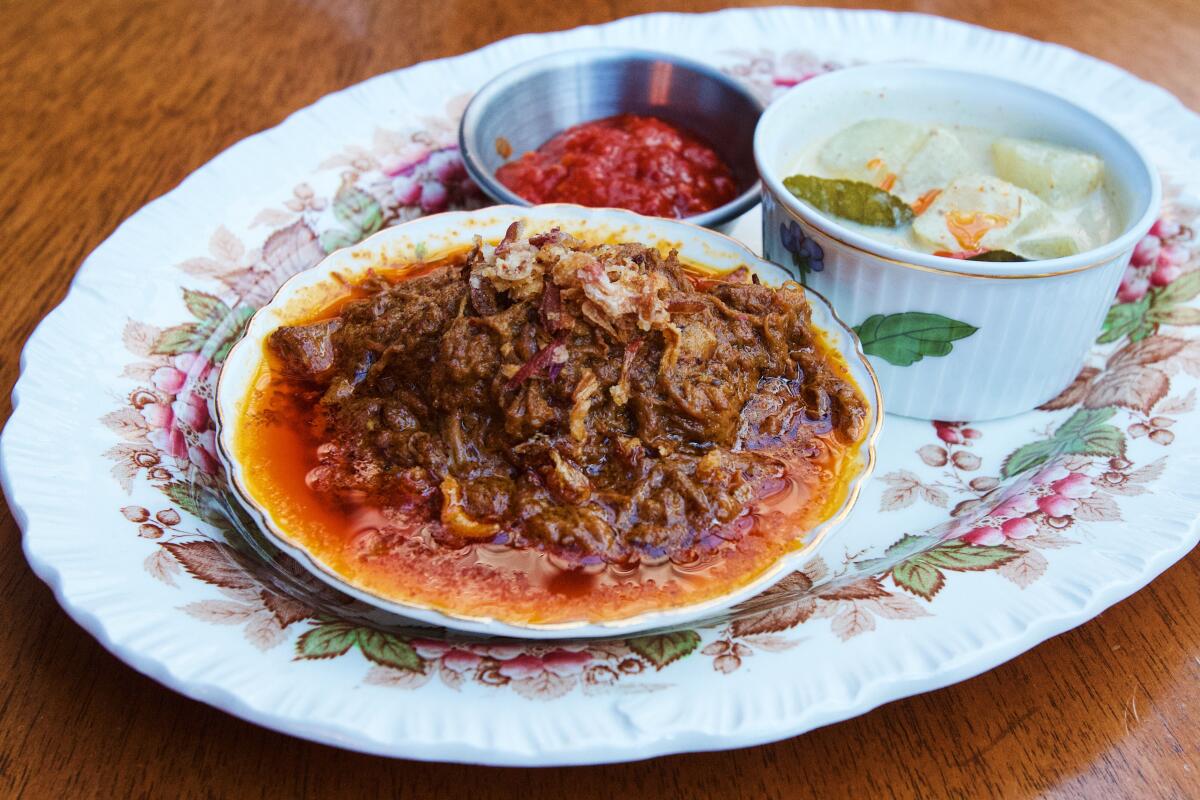 A small bowl of beef rendang with crispy shallots on a porcelain platter with chili at Cobi's in Santa Monica.