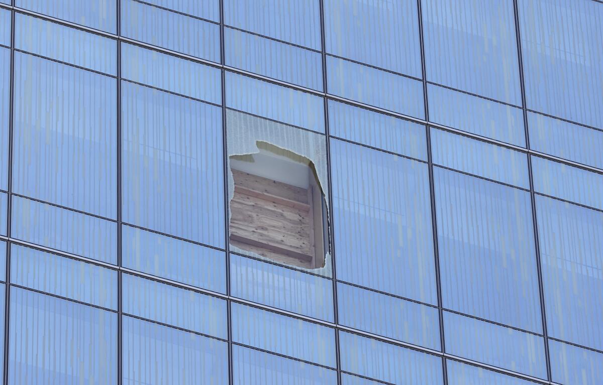 Wood panels behind a hole in a glass window on a high-rise building