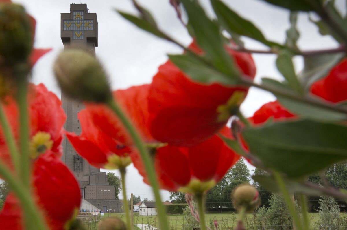 FILE - Red poppies bloom in front of the World War I Ijzertoren (Yser Tower) Monument in Diksmuide, Belgium, June 17, 2014. In Belgium, where bodies of World War I are still being found in Flanders Fields to this day, the Yser Tower contains an inscription of "No more war", in four languages so no one misses the point. (AP Photo/Virginia Mayo, File)