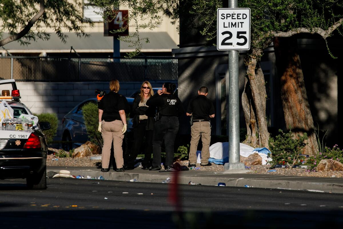 Crime scene investigators stand by a body along Las Vegas' Reno Avenue on Monday morning, in the aftermath of the mass shooting that left at least 58 dead and more than 500 injured.