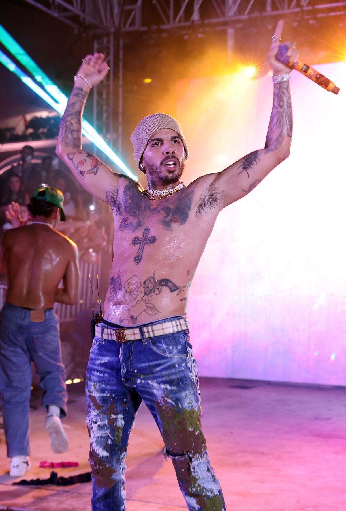 A man in jeans and no shirt performing onstage.