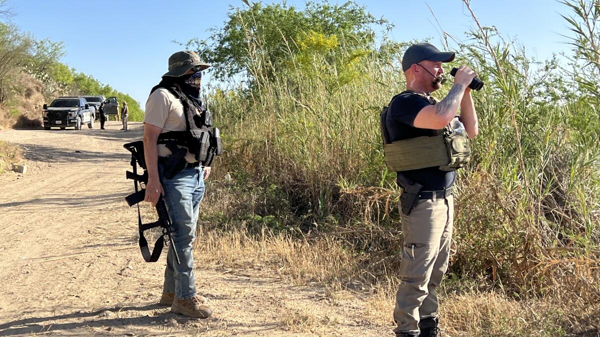 Patriots for America leader Sam Hall, right, on patrol as members confer with local law enforcement.