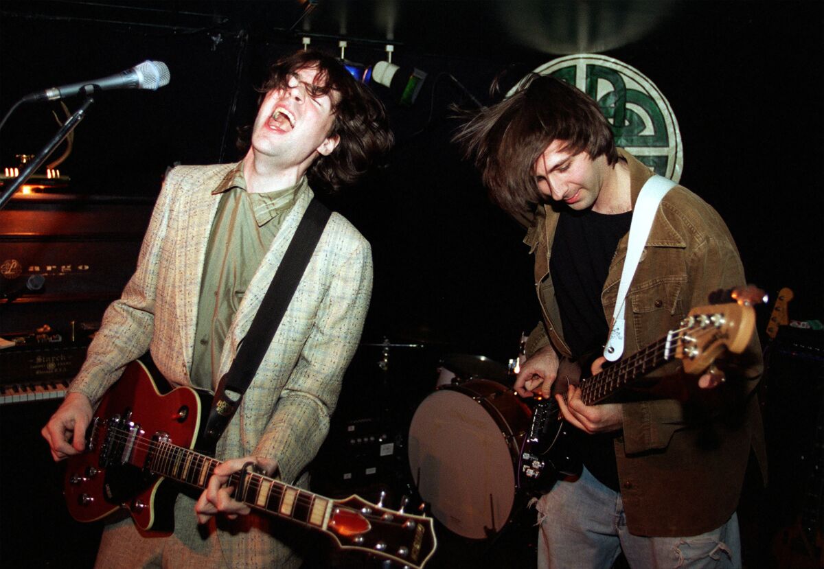 Two male rock musicians sing and play guitar onstage