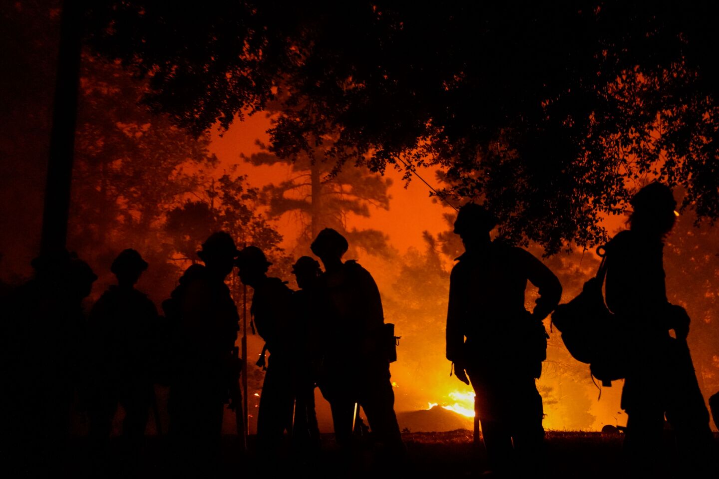 Firefighters are silhouetted against flames in Big Creek, Calif.