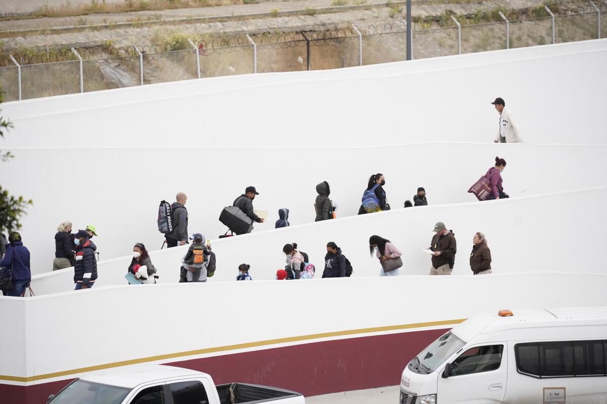 A group of asylum seekers walk up a series of ramps.