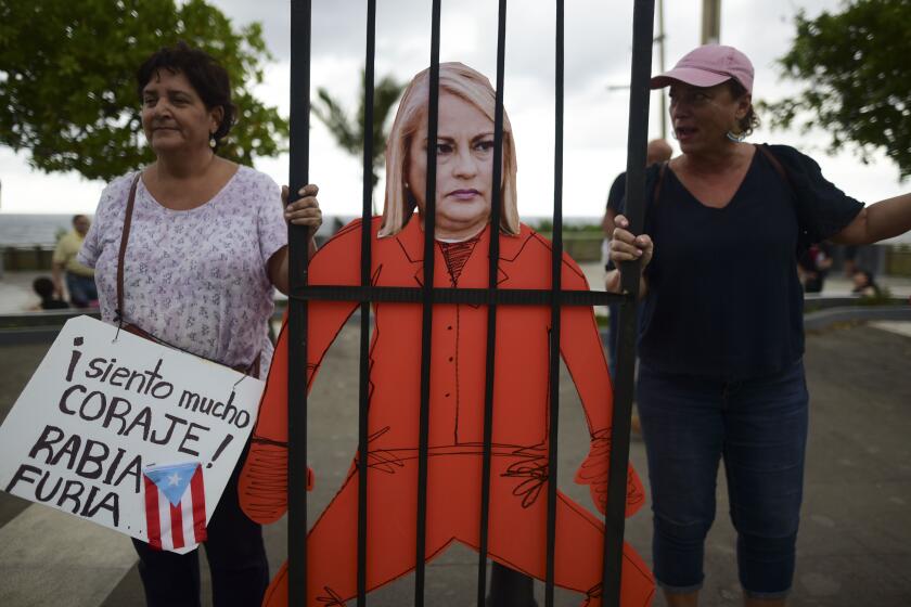 Protesters hold an image of Gov. Wanda Vázquez during a protest organized by Puerto Rican singer Rene Perez of Calle 13 over emergency aid that until recently sat unused in a warehouse amid ongoing earthquakes, in San Juan, Puerto Rico, Thursday, Jan. 23, 2020. Protesters are demanding Vázquez's ouster. (AP Photo/Carlos Giusti)