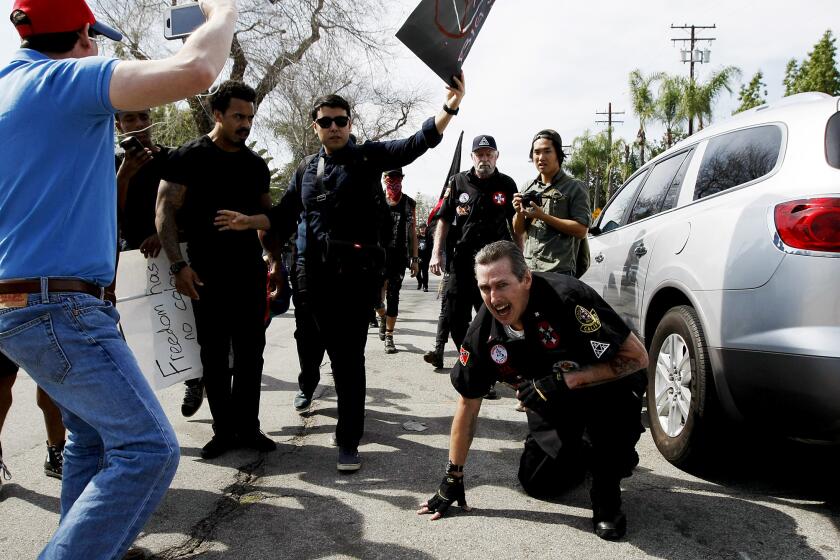 Protesters taunt an injured Ku Klux Klansman after members of the KKK tried to start a "White Lives Matter" rally at Pearson Park in Anaheim. Witnesses said the Klansmen used the point of a flagpole as a weapon while fighting with protesters.