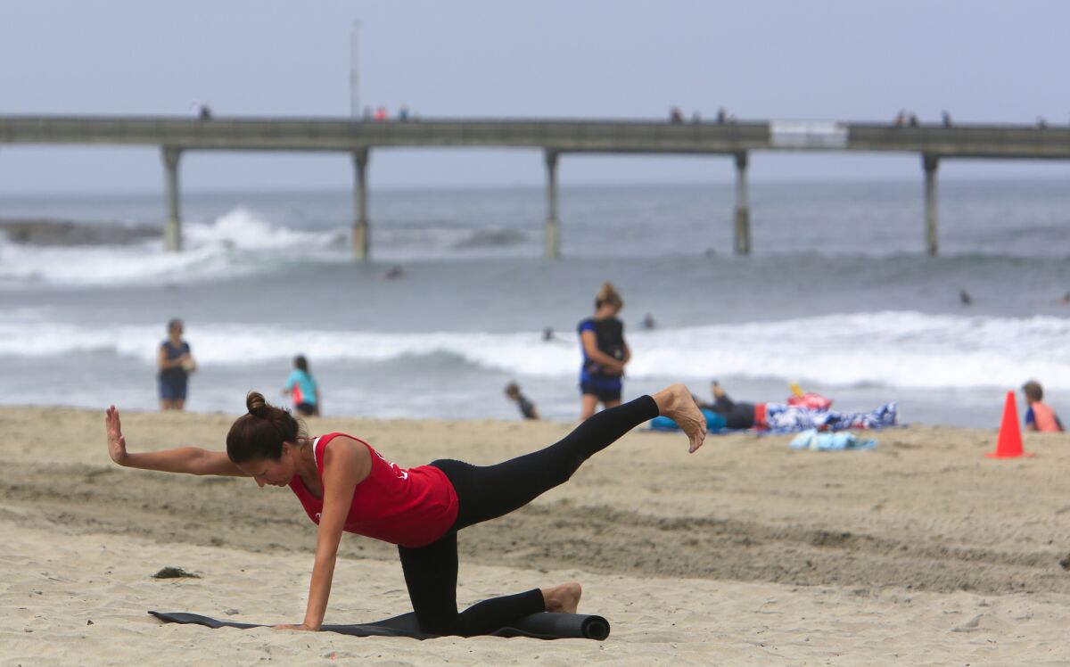 Cherelyn Steele of Pacific Beach does yoga stretches near the Ocean Beach Pier.