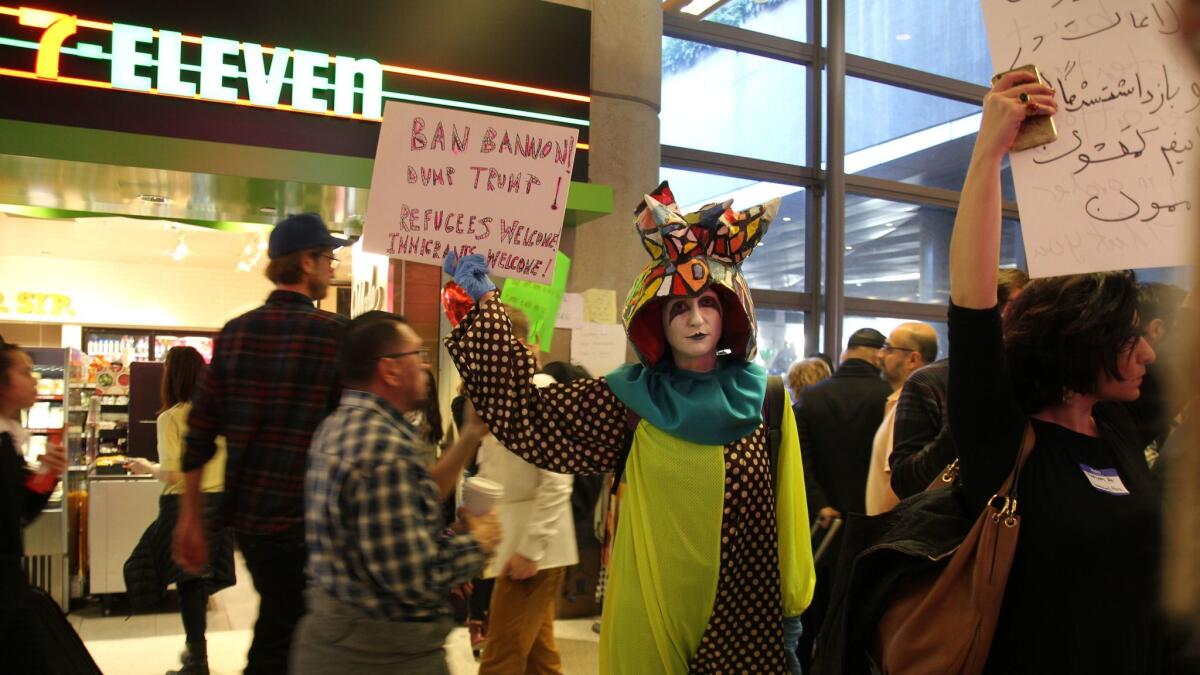 Artist Rachel Mason, dressed as her character FutureClown, stands among protestors at the arrivals gate at Tom Bradley International Airport.