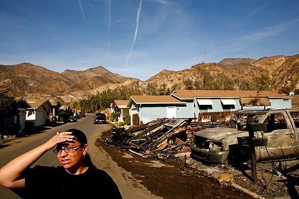 Katrina Vieane walks along her street in Oakridge Mobile Home Park, surveying the damage to her neighborhood in Sylmar's Sayre fire. Her house was not destroyed, but she can't stay there because of damage to the park's infrastructure. She and her children have moved to a nearby apartment.