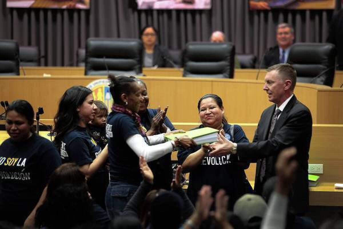 Latrice Gamble hands a binder full of parent-trigger petitions to L.A. Unified Supt. John Deasy. More than 100 parents from 24th Street Elementary were greeted cordially by Deasy.