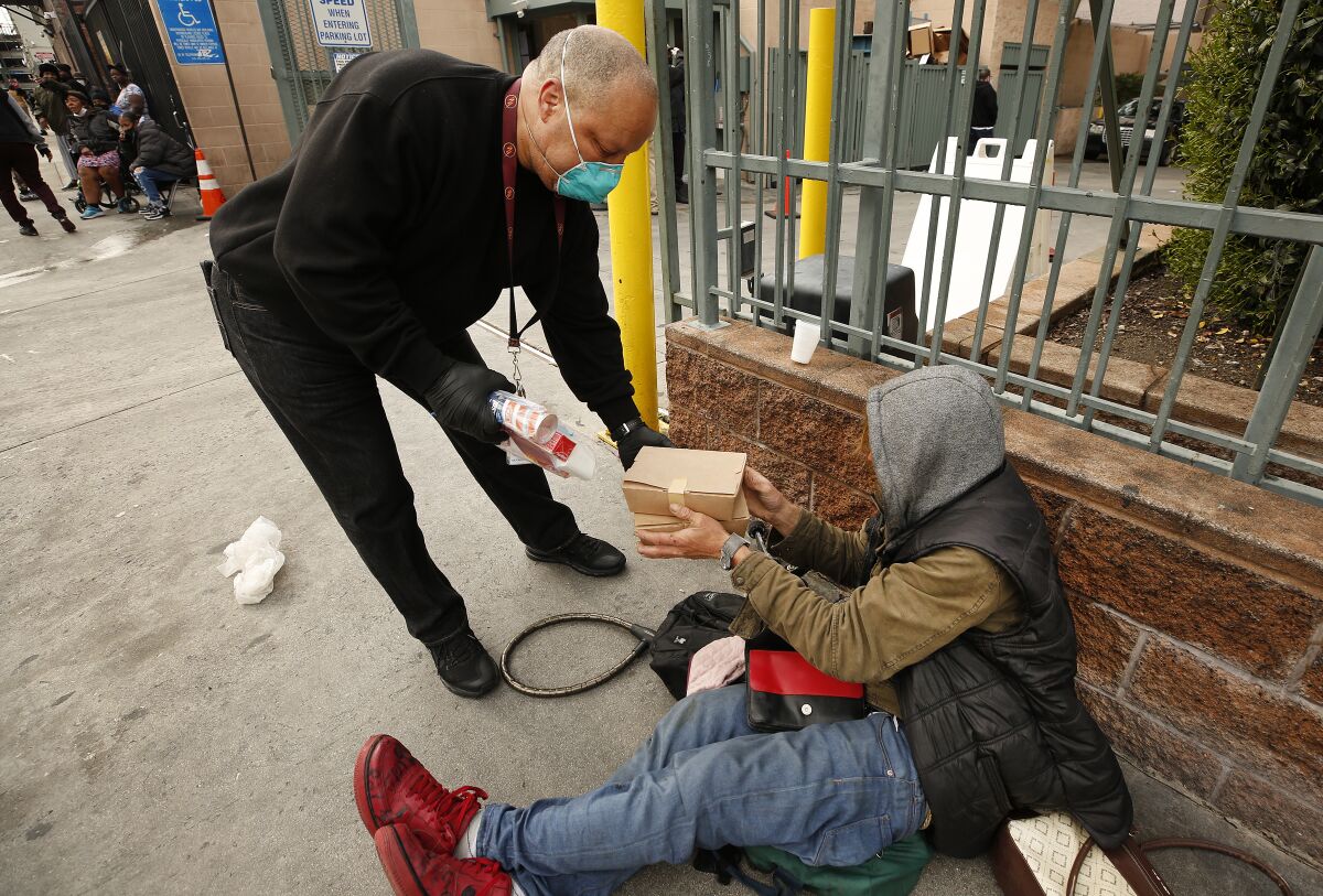 Ralph Sutton, an outreach coordinator for the Los Angeles Mission in skid row, hands Brent Kostanski a box of food.