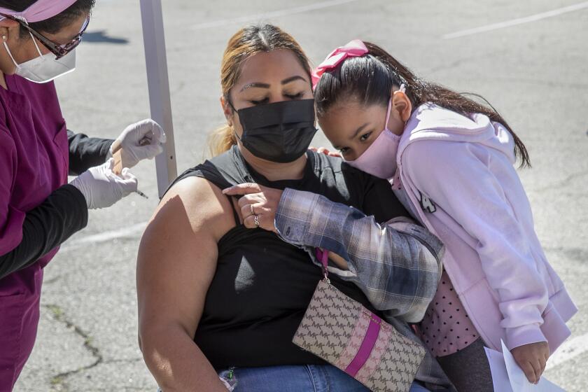 Ana Vidales Torres, 42, is joined by her 6-year-old daughter Talia as she receives a COVID-19 vaccine shot in Pacoima.