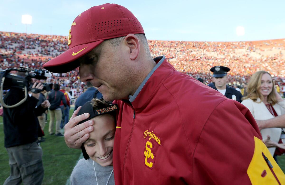 USC Coach Clay Helton embraces his son after a 40-21 victory over UCLA on Nov. 28 at the Coliseum.
