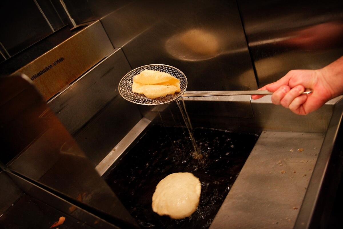 A taco shell emerges from a deep fryer